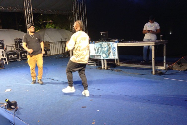 Com uma nota de R$100,00 ao fundo, rappers levam sua mensagem no palco da Fenapraça; veja ao vivo