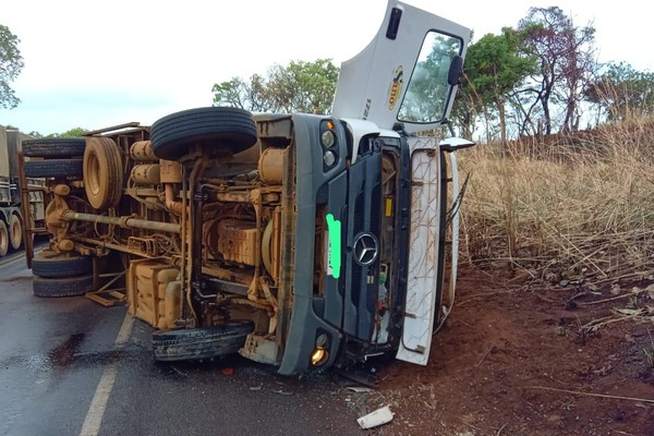 Motorista e passageiro ficam feridos após caminhão deslizar em pista molhada e tombar, na BR352