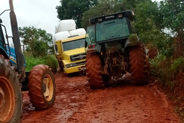 Caminhões precisam ser arrastados por tratores em estrada rural precária em Patos de Minas
