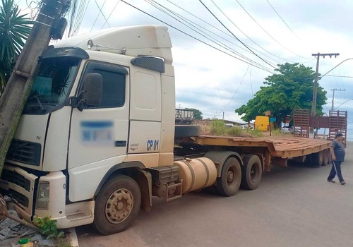 Carreta prancha desgovernada vai parar em poste e deixa estrutura sustentada pela fiação