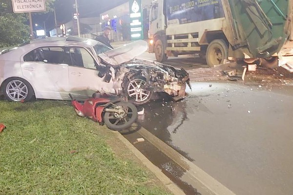 Carro fica destruído após bater em caminhão de coleta de lixo e atingir motoneta na Avenida JK