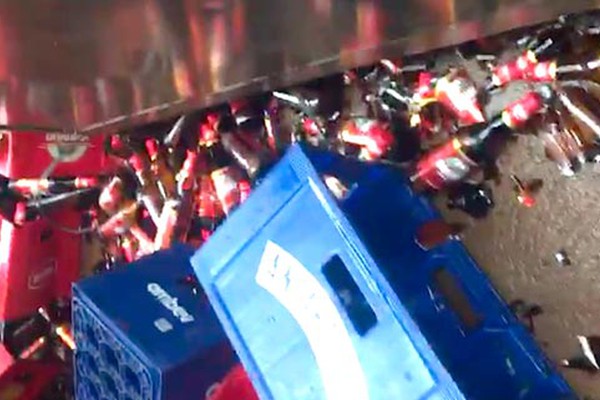 Caminhão de cerveja cai em buraco e desperdiça centenas de garrafas da bebida na calçada de bar 
