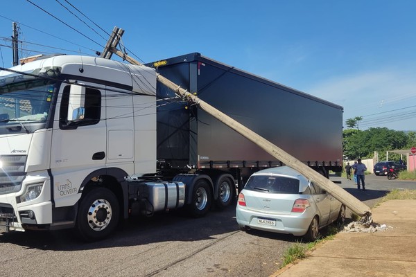 Caminhão arrasta a fiação e derruba poste de iluminação em cima de carro em Patos de Minas